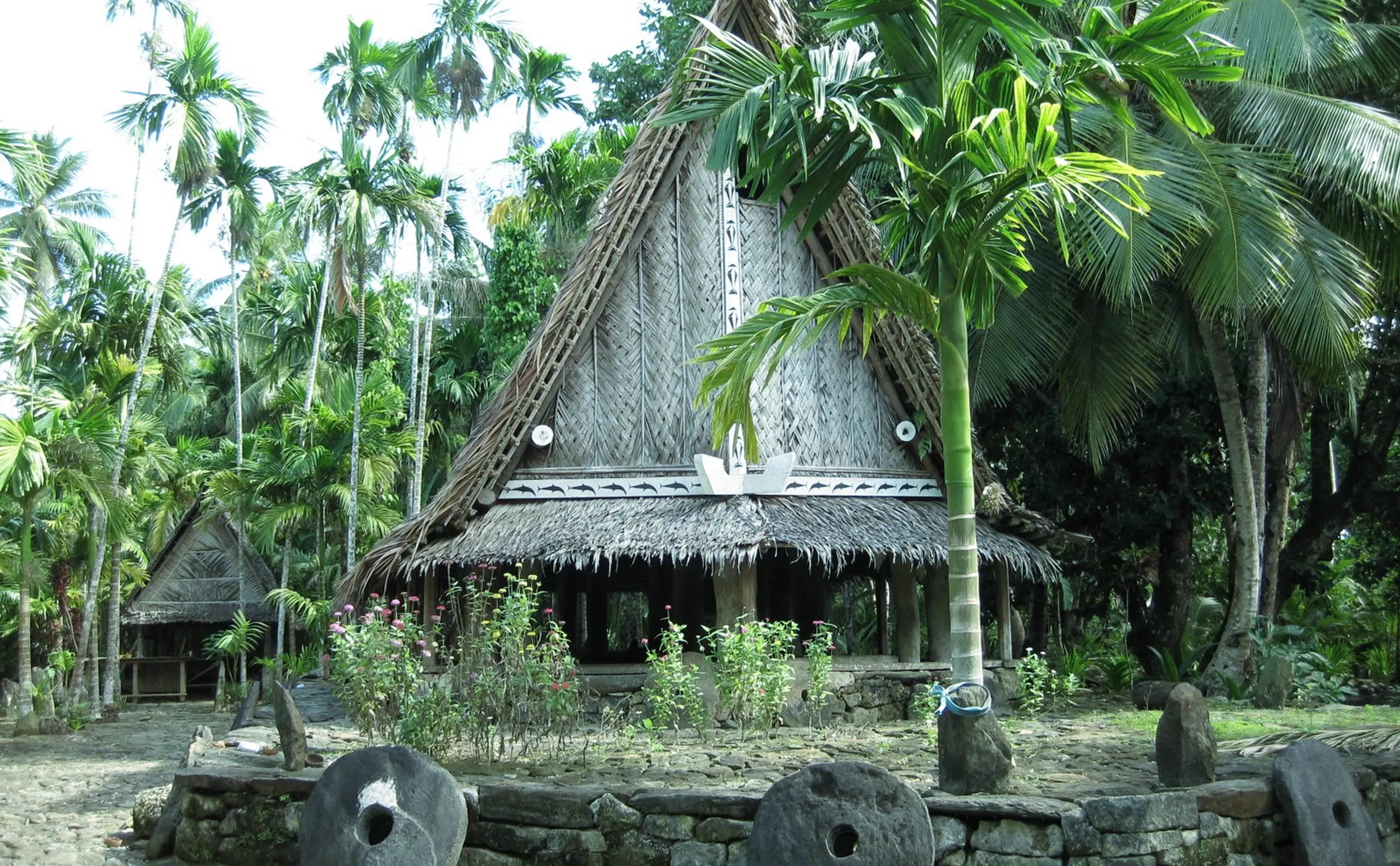 Traditional Micronesian community meeting house (Bai) surrounded by palm trees.